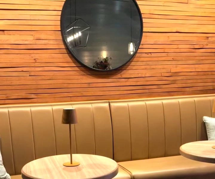 A banquette table, brass lamp and convex mirror