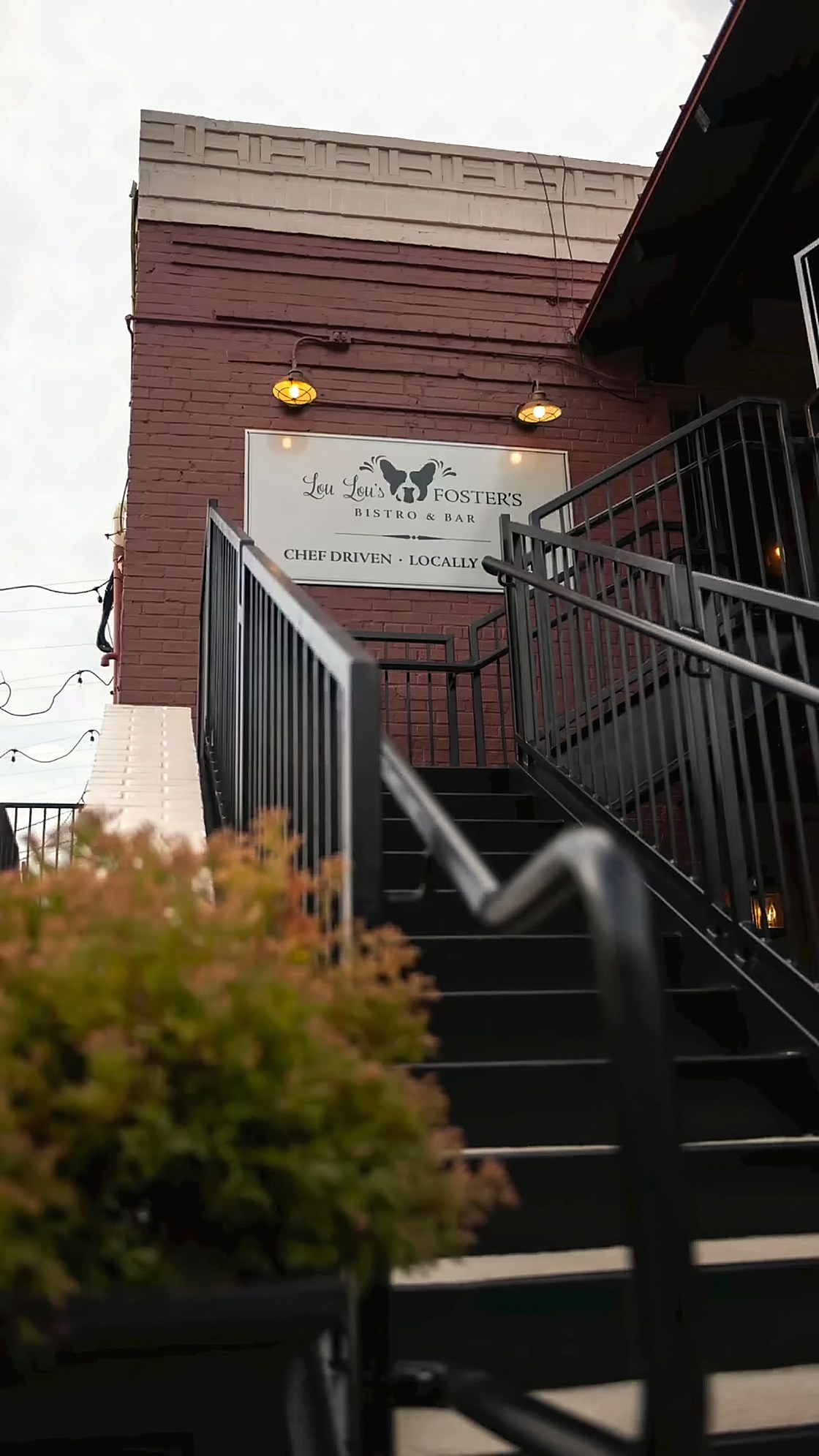 The steel staircase running up the brick to Foster's Bar, with the Lou Lou's and Foster's sign mounted at the landing