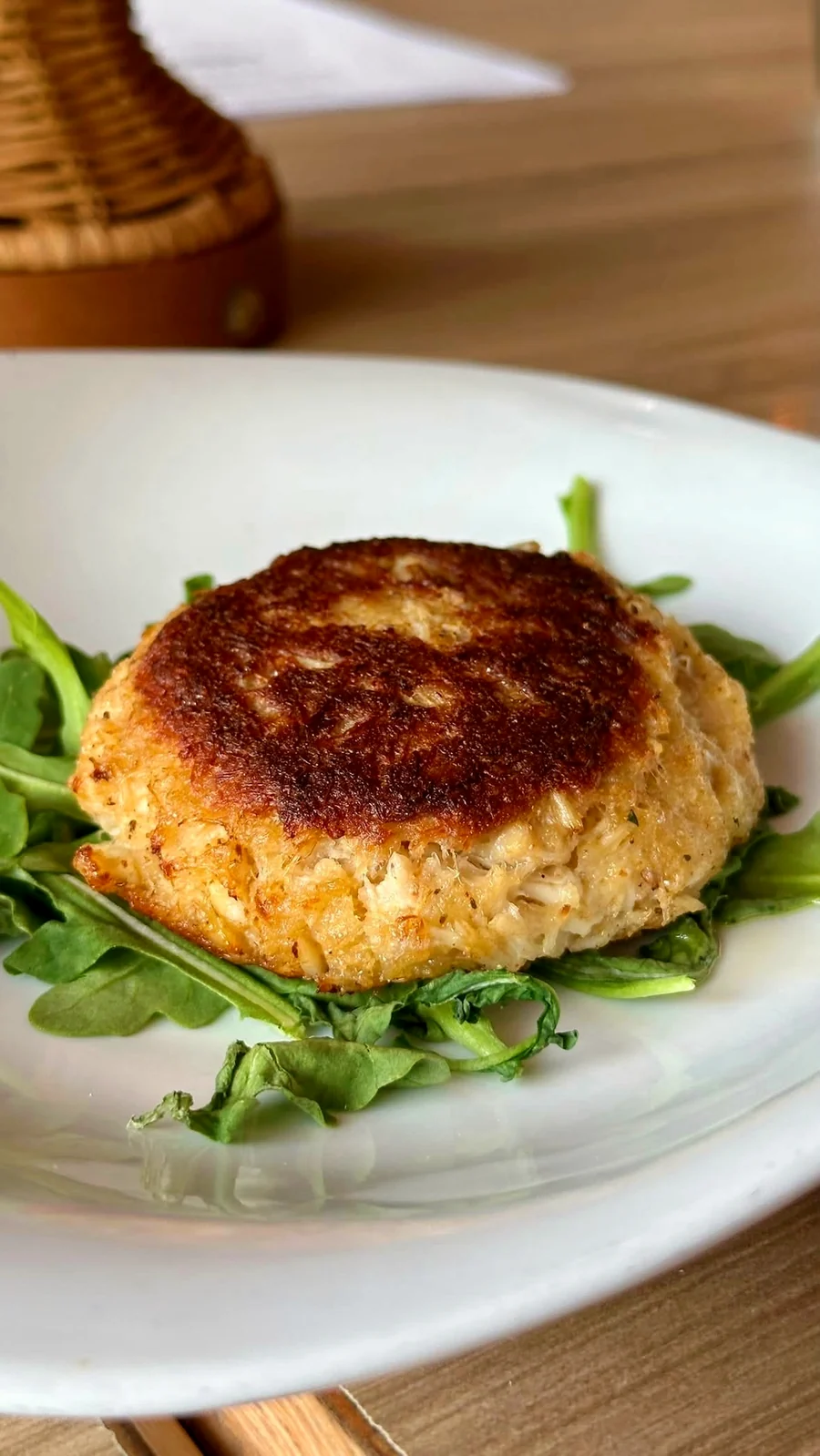One crab cake, on greens