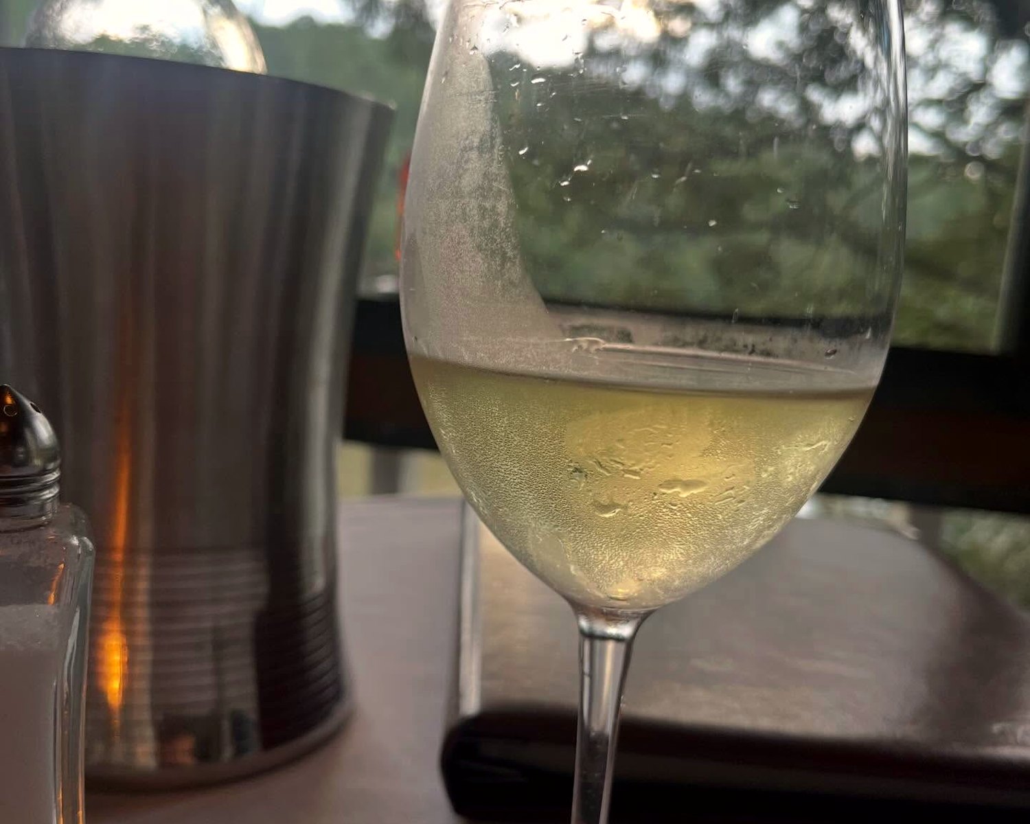 A glass of cold white wine beside an ice bucket in the evening light